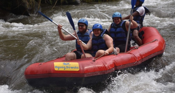 Rafting boats navigate the rapids of the Ayung River with participants wearing helmets and life jackets
